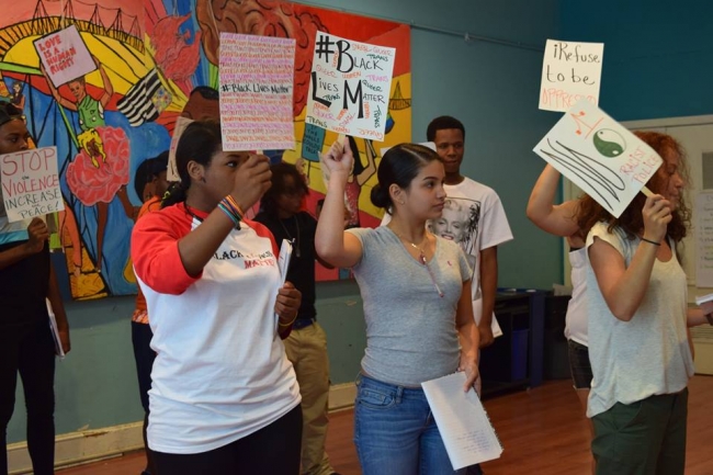 Group of individuals in a class holding different signs with their own writing