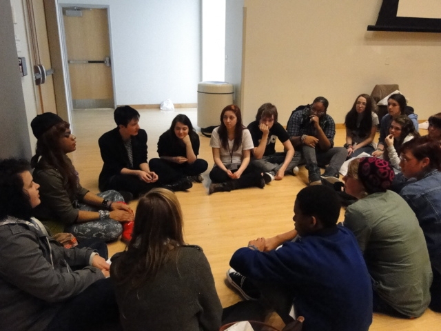 Attic youth group sitting in a circle on the floor in a room.